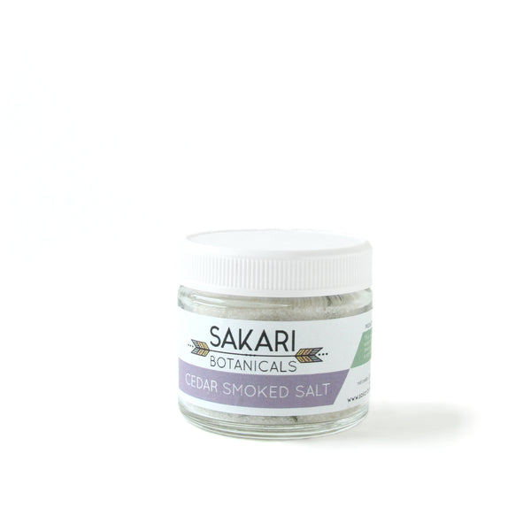 A jar of Cedar smoked sea salt from Sakari Farms on a white background.