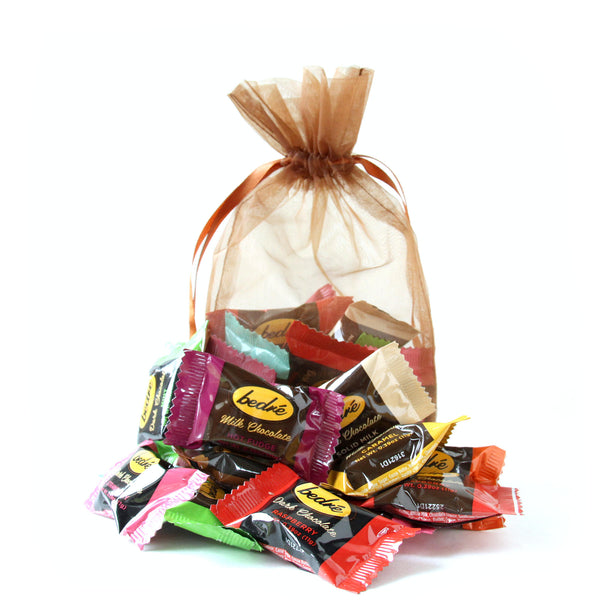 A gauze bag with an assortment of 12 individually wrapped chocolate Meltaways from Bedré chocolatier, all on a white background.